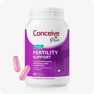 Conceive Plus Women's Fertility Support (ES) supplement bottle for female reproductive health with 60 vegetarian capsules, shown with two loose pink capsules beside a white and purple container labeled in Spanish, placed on a clean white background.
