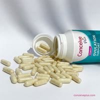 Open bottle of Conceive Plus ovulation support supplements with capsules on a white background