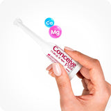 Conceive Plus Fertility Lubricant Pack (ES) with prefilled applicator, shown held between fingers with neutral nails, alongside floating Ca and Mg ions icons to indicate active mineral ingredients. The white slim applicator has pink branding text.