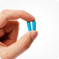 Conceive Plus Men's Fertility Support (ES) daily capsule format for male fertility health. The image features a close-up of two turquoise capsules gently held between thumb and the index finger against a white background.