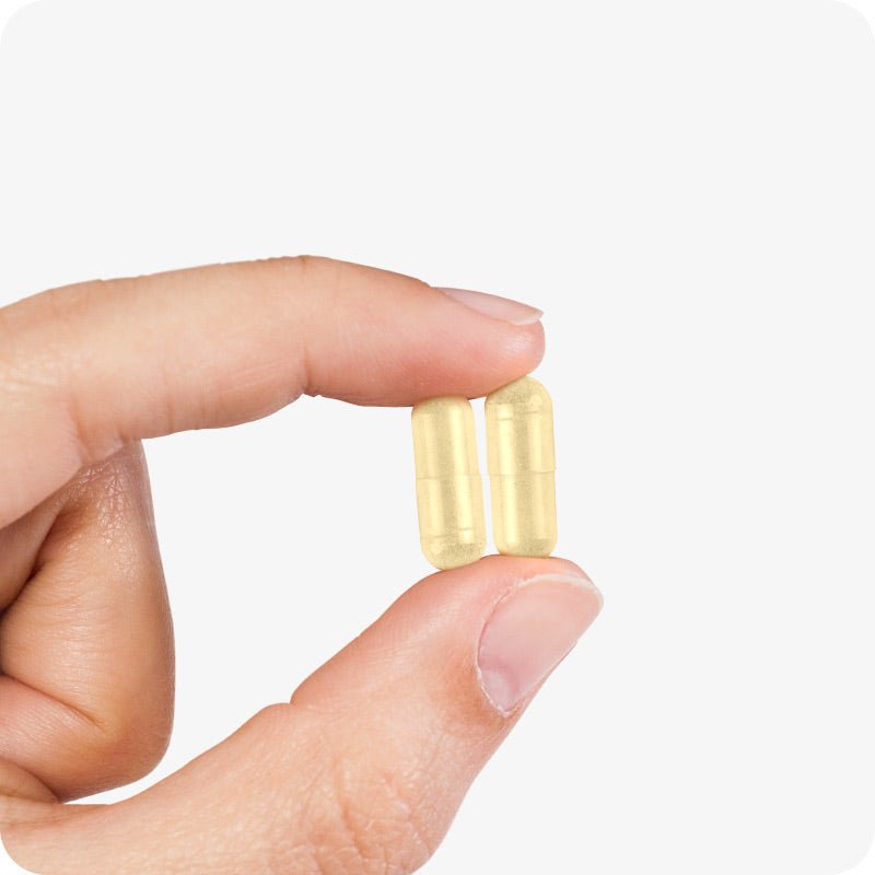 Conceive Plus Men's Motility Support (ES) fertility supplement capsules designed to aid male reproductive health shown as two light yellow capsules held between the thumb and index finger of a hand against a light grey background.