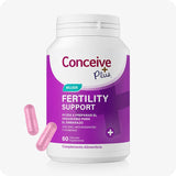 Conceive Plus Ovulation Bundle (ES) featuring the Women's Fertility Support bottle in Spanish packaging with a bold purple label and two visible pink vegetarian capsules placed beside the bottle to illustrate supplement form.